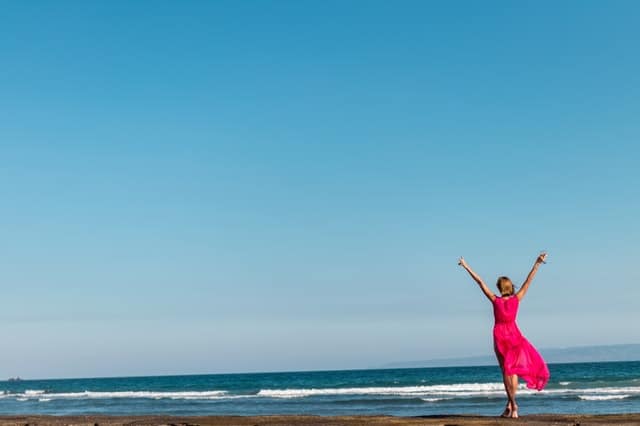 une femme en robe rouge debout sur la côte