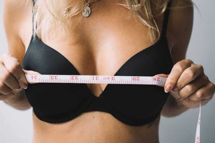 une femme mesure ses seins avec un centimètre
