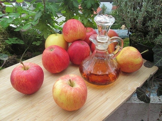 Des pommes fraîches et une bouteille de vinaigre de cidre de pomme sur la table
