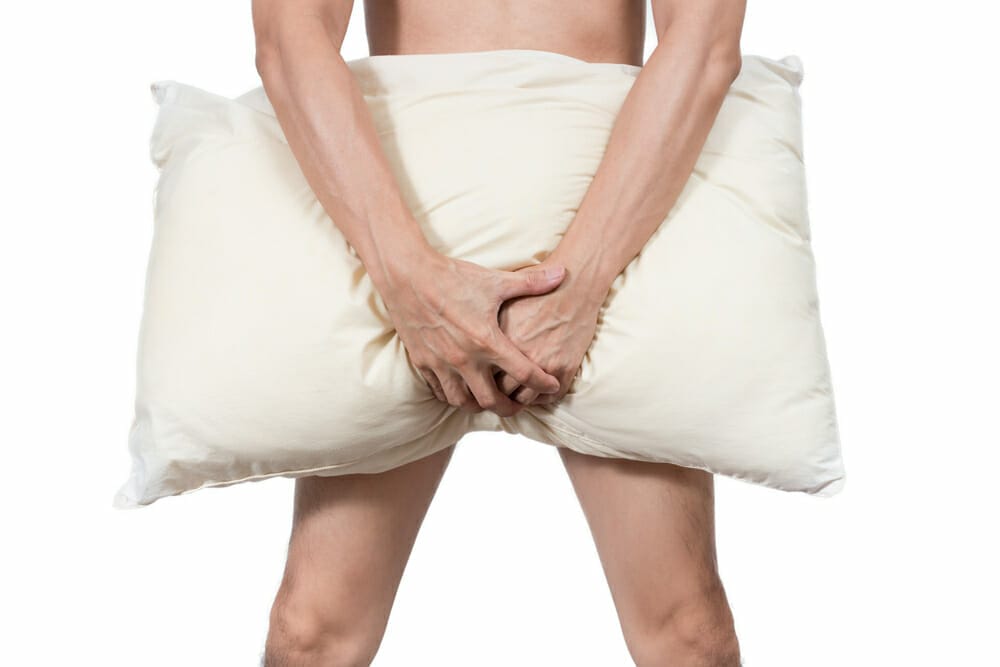  un homme couvre son entrejambe avec un oreiller