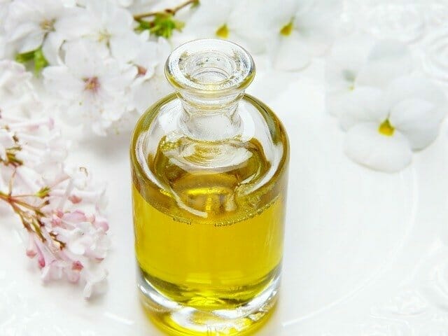  Une bouteille d'huile avec des fleurs à côté
