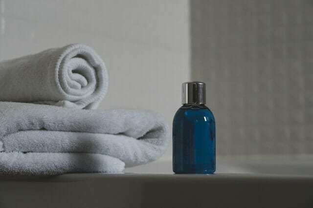  bouteille bleue avec du shampooing, serviettes à côté