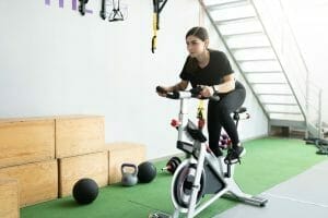  une femme s'entraîne sur un vélo stationnaire