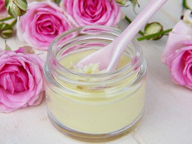  Un pot de crème pour le visage fait maison, à côté des roses.