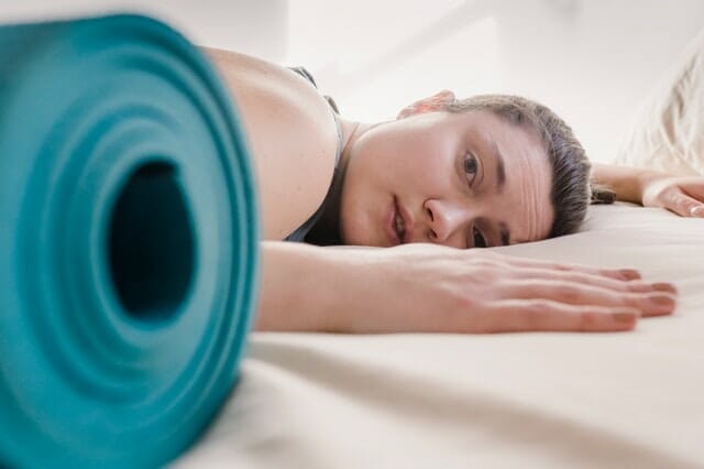  femme épuisée par l'entraînement, à côté d'un tapis d'exercice