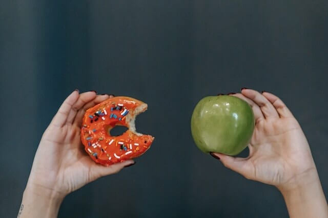  deux mains, l'une tenant une pomme, l'autre un beignet