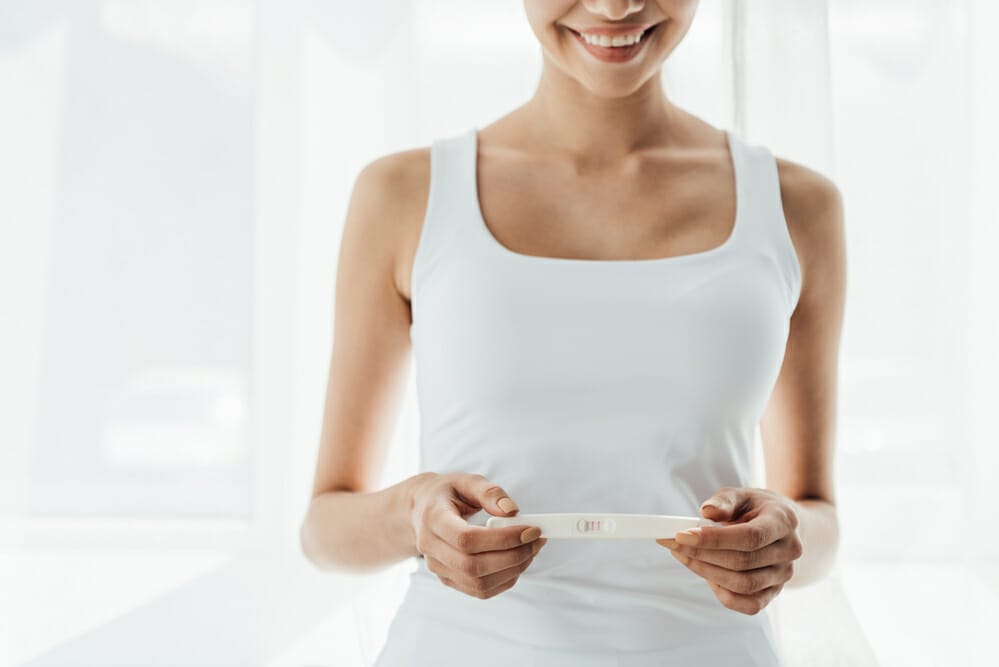  une femme satisfaite tient un test de grossesse positif