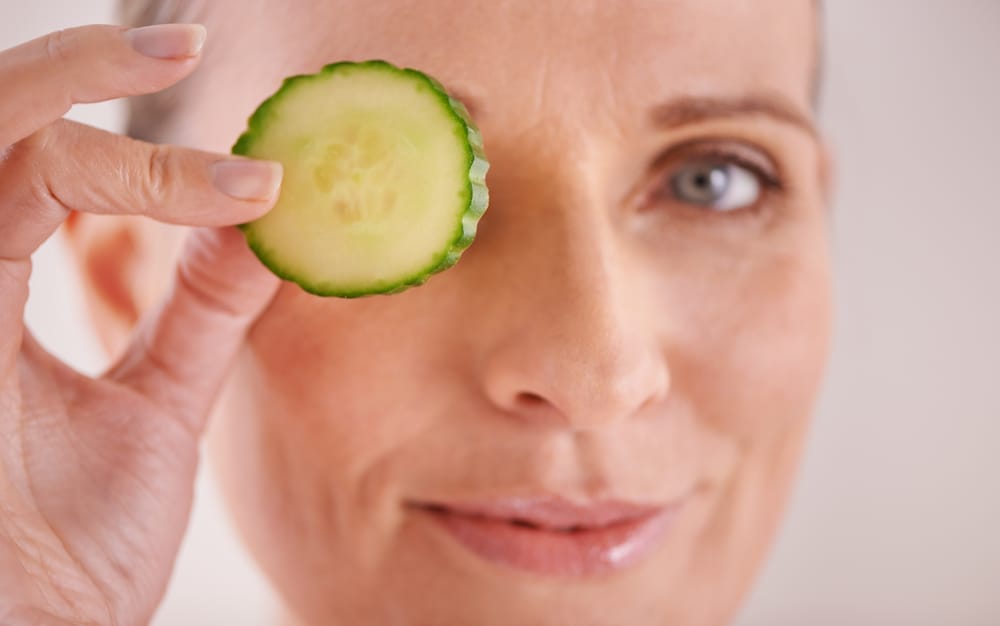  Une femme porte une tranche de concombre à son œil.