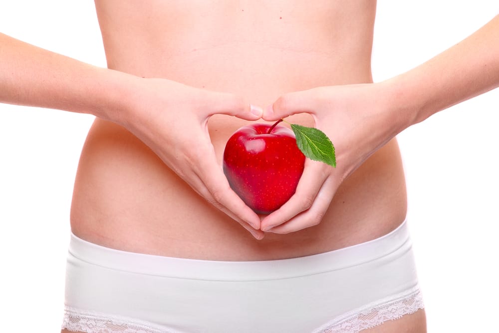  une femme porte une pomme à son estomac